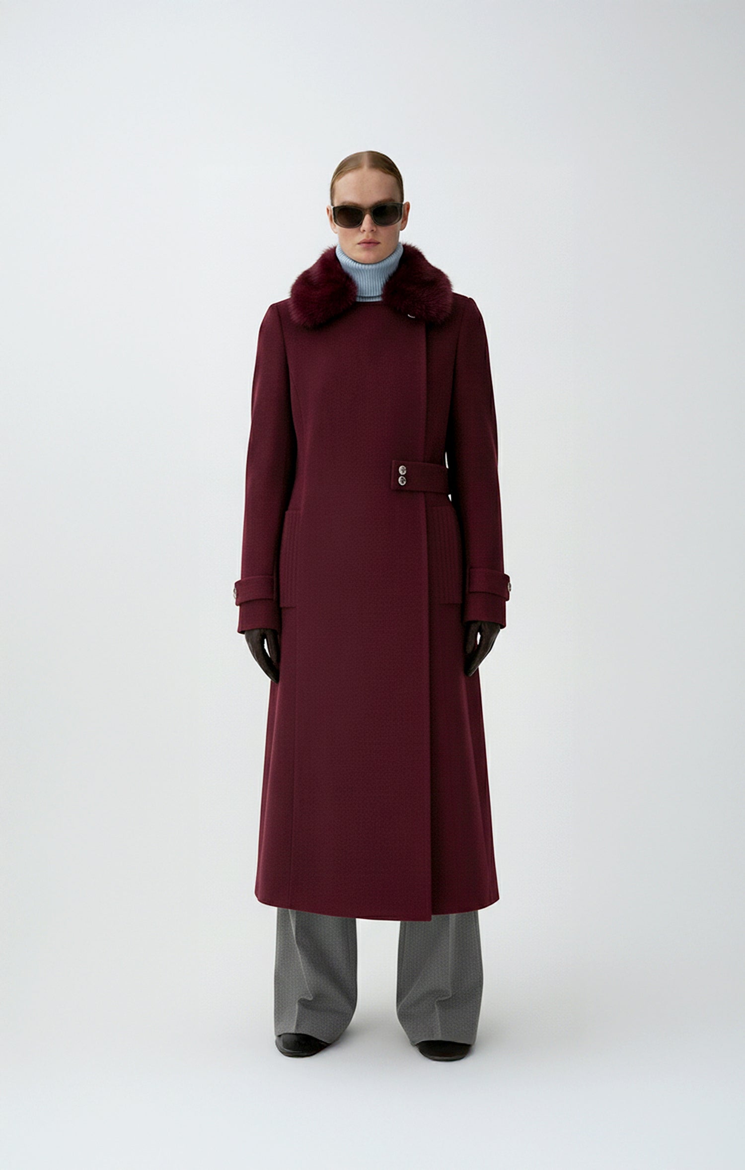 Person wearing a long burgundy wool coat on a white background
